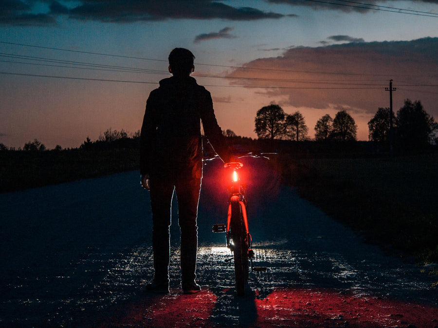 Radfahrer in der Dämmerung mit leuchtendem roten Rücklicht am Fahrrad