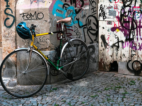 Blauer Fahrradhelm hängt am Lenker eines grün-gelben Rennrads vor einer mit Graffiti bemalten Wand in Berlin