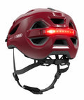 Helm ABUS Urban-I 4.0 chestnut red, schräg von hinten mit LED-Rücklicht